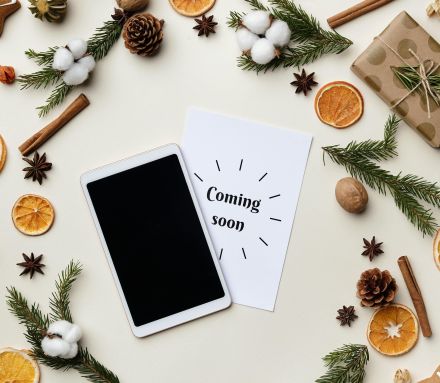 Flatlay featuring holiday decorations with gifts, spices, and a tablet on a light background.